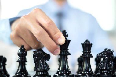 Satranç oynayan iş adamlarının eli liderlik, takipçiler ve ticari başarı stratejilerini gösteriyor.