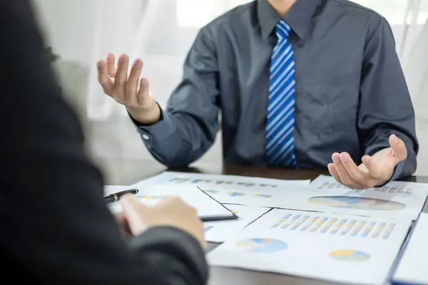 İki iş lideri çizelgeler, finansal grafikler hakkında konuşuyor. Sonuçları gösteren planlama stratejilerini analiz ediyor ve hesaplıyor. Ticari başarı oluşturma süreçlerini de..