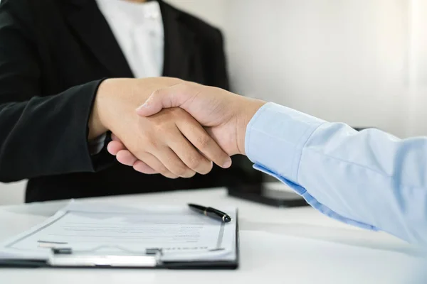 Friendly businessmen and executives shake hands after successful agreement with employment contracts, recruitment, and employment concepts.