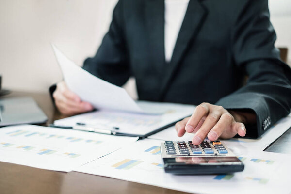 The businessman hand sits at their desks and calculates financial graphs showing the results of their investments planning the process of successful business growth.