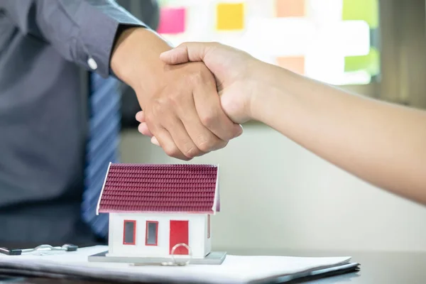 Businessmen and brokers real estate agents shake hand after completing negotiations to buy house insurance and sign contracts. Home insurance concept.
