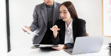 İki iş lideri çizelgeler, finansal grafikler hakkında konuşuyor. Sonuçları gösteren planlama stratejilerini analiz ediyor ve hesaplıyor. Ticari başarı oluşturma süreçlerini de..