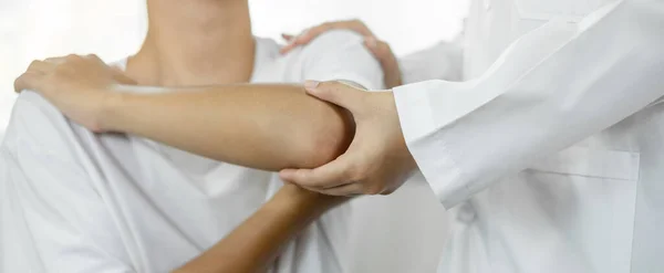 女性理学療法士は 肘の損傷を受けた男性患者を支援し リハビリテーションセンターで患者を検査する 理学療法の概念 — ストック写真