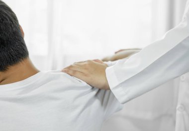 Kadın fizyoterapistler, erkek hastalara omuz sakatlığı olan hastalar için rehabilitasyon merkezinde omuzlarına masaj yapıyorlar. Fizyoterapi kavramları.