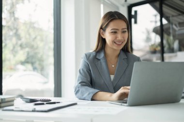 Asyalı iş kadınları masalarında oturur ve yatırımlarıyla ilgili sonuçları gösteren finansal grafikleri hesaplar, başarılı bir iş büyüme süreci planlarlar.