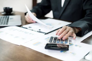 İş adamı masalarında oturur ve başarılı iş büyümesi sürecini planlayan yatırımlarının sonuçlarını gösteren mali grafikleri hesaplar.