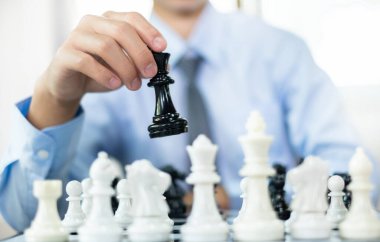 Satranç oynayan iş adamlarının elleri liderlik, takipçiler ve ticari başarı stratejilerini gösteriyor.