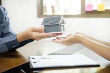 Emlakçı, kira sözleşmesini imzalayıp ev sigortasını resmen tamamladıktan sonra evi yeni sahibinin müşterisine verir. Kiralama ve sigorta kavramları.