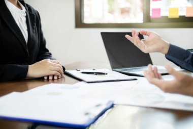 İki iş lideri çizelgeler, finansal grafikler hakkında konuşuyor. Sonuçları gösteren planlama stratejilerini analiz ediyor ve hesaplıyor. Ticari başarı oluşturma süreçlerini de..