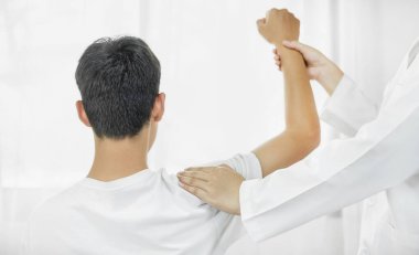 Kadın fizyoterapistler, erkek hastalara omuz yaralanmalarında fiziksel yardım sağlıyor rehabilitasyon merkezinde kas tedavisi için omuzlarına masaj yapıyorlar. Fizyoterapi kavramları.