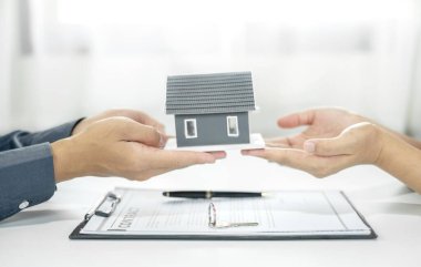 Emlakçı, kira sözleşmesini imzalayıp ev sigortasını resmen tamamladıktan sonra evi yeni sahibinin müşterisine verir. Kiralama ve sigorta kavramları.