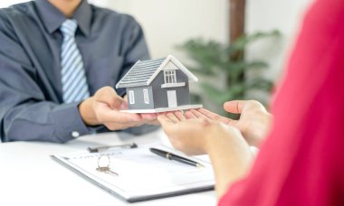 Emlakçı, kira sözleşmesini imzalayıp ev sigortasını resmen tamamladıktan sonra evi yeni sahibinin müşterisine verir. Kiralama ve sigorta kavramları.