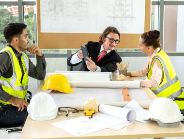 Erkek ve kadın mühendisler ve mimarlardan oluşan bir ekip, çalışma ekibi, inşaat planlarını tartışıyor ve çiziyor, baskı yapıyor, inşaat alanlarında yazıyor..
