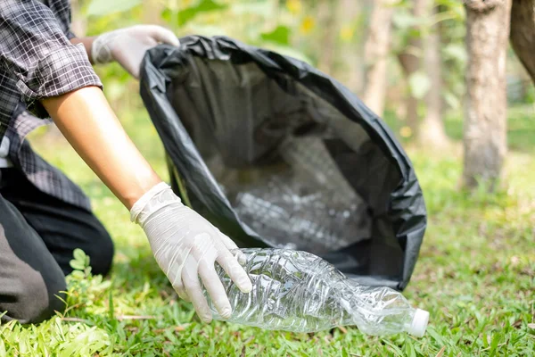 garbage collection, volunteer team picking up plastic bottles, putting garbage in black garbage bags to clean up at parks, avoiding pollution, and being friendly to the environment and ecosystem.