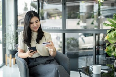 Asyalı kız internet üzerinden alışveriş yapıyor ve akıllı telefon kullanıyor. Cep telefonu numaralarını internet mağazasından satın almak ve ödemek için cep telefonu uygulamasına girin..