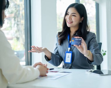 Asyalı müşteri hizmetleri temsilcileri çalışır ve gülümserler müşterilere kredi kartı satarlar. Ofisteki sigorta planını seç.