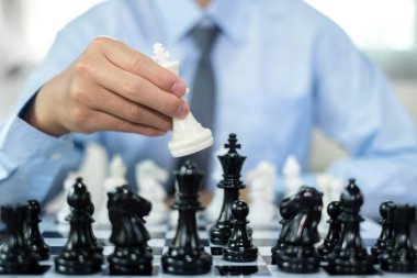 Satranç oynayan iş adamlarının eli liderlik, takipçiler ve ticari başarı stratejilerini gösteriyor.
