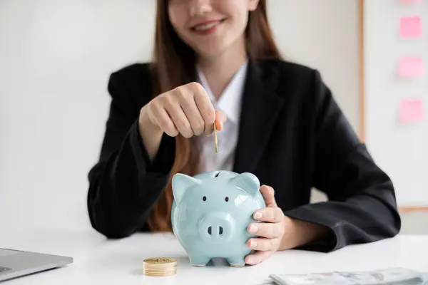 Asian woman putting coin into piggy bank. Saving money with coins Step into a business that is growing to be successful and save for retirement concepts.