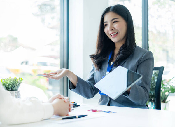 Asian business customer service representatives work and smile serve sell credit card to customers. choosing insurance plan in office.