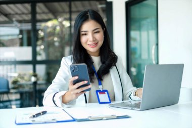 Asyalı iş kadını masalarında oturup yatırımlarıyla ilgili sonuçları gösteren finansal grafikleri hesaplıyor ve başarılı bir iş büyüme süreci planlıyor.