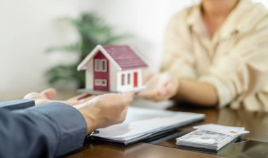 Emlakçı, kira sözleşmesini imzalayıp ev sigortasını resmen tamamladıktan sonra evi yeni sahibinin müşterisine verir. Kiralama ve sigorta kavramları.