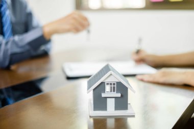 Ev modeli olan bir emlakçı, ev sigortası yaptırmak ve resmi pazarlıklar tamamlandıktan sonra sözleşmeyi imzalamak için müşterilerle görüşüyor..