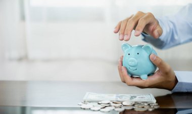 El domuz kumbarasını korur, bir yığın madeni parayla tasarruf ettirir, başarılı bir büyüyen işe adım atar ve emeklilik için biriktirir. Emeklilik Tasarruf kavramı.