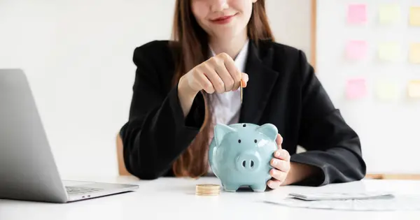 Asian woman putting coin into piggy bank. Saving money with coins Step into a business that is growing to be successful and save for retirement concepts.
