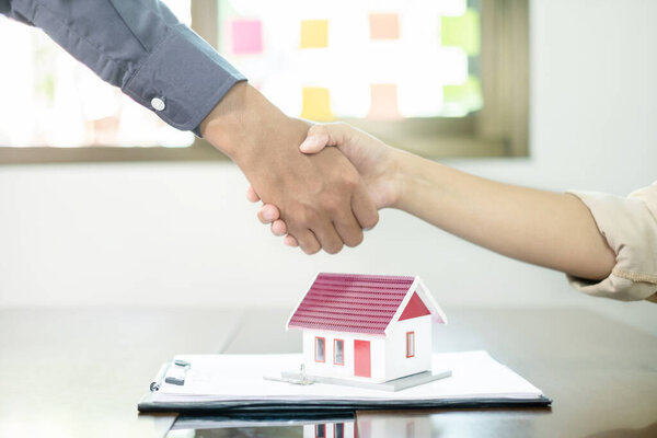 Businessmen and brokers real estate agents shake hand after completing negotiations to buy houses insurance and sign contracts. Home insurance concept.