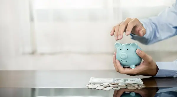 Hand protects a piggy bank save money with a pile of coins, steps into a successful growing business, and saves it for retirement. Retirement Savings concept.