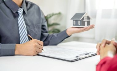 Ev modeli olan bir emlakçı ev sigortası almak için müşterilerle konuşuyor. Ev sigortası kavramı.