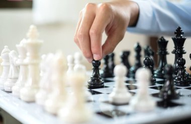 Satranç oynayan iş adamlarının eli liderlik, takipçiler ve ticari başarı stratejilerini gösteriyor.