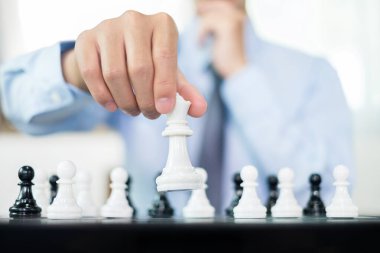 Satranç oynayan iş adamlarının eli liderlik, takipçiler ve ticari başarı stratejilerini gösteriyor.