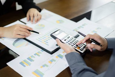 İş dünyası liderleri, sonuçları gösteren grafikler, planlama stratejileri ve ticari başarı oluşturma süreçlerini analiz ediyor ve hesaplıyor.