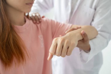 Kadın fizyoterapistler dirsek yaralanması olan hastalara yardım ediyor ve rehabilitasyon merkezlerindeki hastaları muayene ediyorlar. Fizyoterapi kavramları.