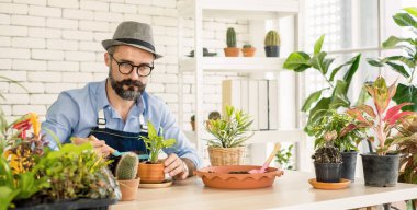 An elderly man wearing glasses is happy with tree care and decoration. It is a hobby of home gardening, living happily after retirement.
