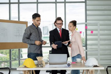 Erkek ve kadın mühendisler ve mimarlardan oluşan bir ekip, çalışma ekibi, inşaat planlarını tartışıyor ve çiziyor, baskı yapıyor, inşaat alanlarında yazıyor..