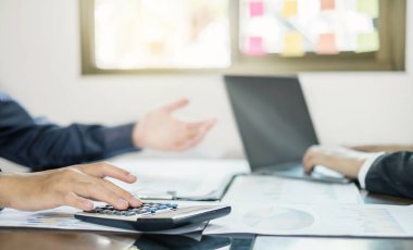 İki iş lideri çizelgeler, finansal grafikler hakkında konuşuyor. Sonuçları gösteren planlama stratejilerini analiz ediyor ve hesaplıyor. Ticari başarı oluşturma süreçlerini de..