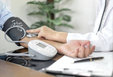 Kadın doktor kan basıncını ölçtü, hasta kalp atışlarını inceledi ve sağlık hizmetleri hakkında konuşmak için oturdu. sağlık hizmeti kavramı.
