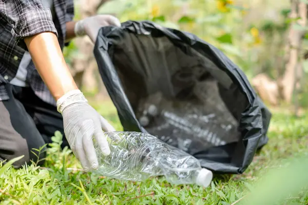 garbage collection, volunteer team pick up plastic bottles, put garbage in black garbage bags to clean up at parks, avoid pollution, be friendly to the environment and ecosystem.