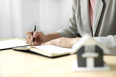 Emlak yatırımında çalışan ajanlar ve ev sigortası sözleşmelerini müşterilerin satın alınmasını onaylayan ev sigortası anlaşmaları uyarınca imzalıyorlar. Ev sigortası kavramı.