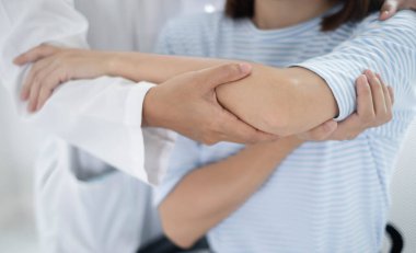 Kadın fizyoterapistler, dirsek yaralanması olan kadın hastalara rehabilitasyon merkezlerindeki hastaları muayene etmeleri için fiziksel yardım sağlıyorlar. Fizyoterapi kavramları.