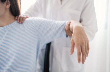 Kadın fizyoterapistler, omuz yaralanması olan hastalara rehabilitasyon merkezinde kas tedavisi için omuzlarına masaj yapıyorlar. Fizyoterapi kavramları.