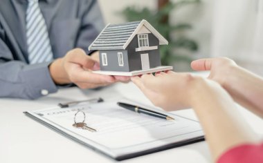 Emlakçı, kira sözleşmesini imzalayıp ev sigortasını resmen tamamladıktan sonra evi yeni sahibinin müşterisine verir. Kiralama ve sigorta kavramları.