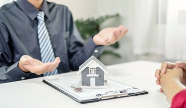 Ev modeli olan bir emlakçı ev sigortası almak için müşterilerle konuşuyor. Ev sigortası kavramı.