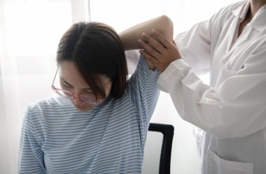 Kadın fizyoterapistler, dirsek yaralanması olan kadın hastalara rehabilitasyon merkezlerindeki hastaları muayene etmeleri için fiziksel yardım sağlıyorlar. Fizyoterapi kavramları.