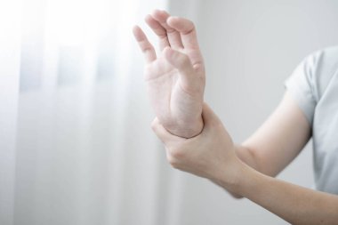 Bileğinde ağrı, avucunda uyuşukluk ve ağrı olan bir kadın elinin sinir uçlarında ağrı ve karıncalanma vardır. Bu ofiste uzun süre oturup çalışmanın bir yan etkisidir..