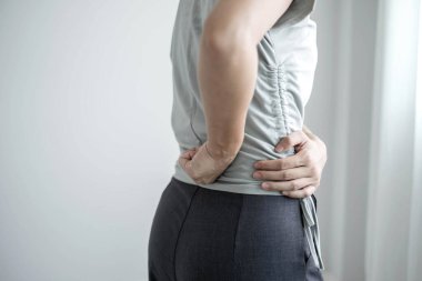 Uzun süre çalışan bir kadının sırtında ağrı vardı. Ofiste sıkı çalışırken rahatlamak ve dinlenmek için esnemek..