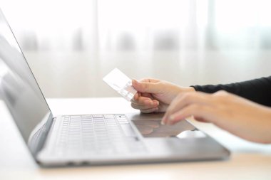 Asyalı kız internet üzerinden alışveriş yapıyor ve dizüstü bilgisayar kullanıyor. Cep telefonu numaralarını internet mağazasından satın almak ve ödemek için cep telefonu uygulamasına girin..