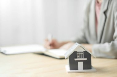 Emlak yatırımında çalışan ajanlar ve ev sigortası sözleşmelerini müşterilerin satın alınmasını onaylayan ev sigortası anlaşmaları uyarınca imzalıyorlar. Ev sigortası kavramı.